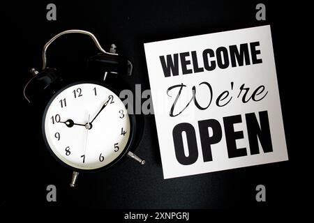 Willkommen Wir haben OFFENEN Text mit Wecker auf schwarzem Hintergrund Stockfoto