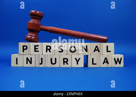 Personenschäden Gesetz Buchstaben mit Holzblöcken Alphabet Buchstaben und Gavel auf blauem Hintergrund Stockfoto