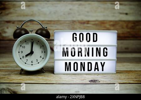 Guten Morgen Montag Text auf LED Leuchtkasten mit Wecker auf hölzernem Hintergrund Stockfoto