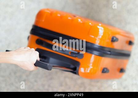 Die Frau hält den orangefarbenen Koffer in der Hand Stockfoto