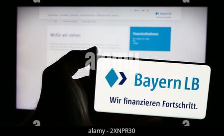 Person mit Smartphone mit Logo der Bayerischen Landesbank (BayernLB) vor der Website. Schwerpunkt auf dem Display des Telefons. Stockfoto