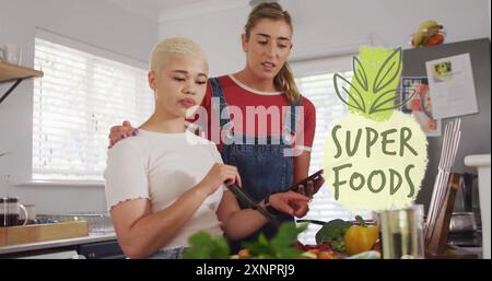 Bild von Super Food Text über diversen weiblichen Paaren, die zu Hause kochen Stockfoto