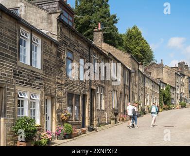 Menschen, die entlang der Howarth Main Street, Yorkshire, England, Großbritannien laufen Stockfoto