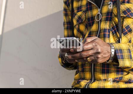 Hände eines afrikaners, der auf seinem Handy tippt Stockfoto