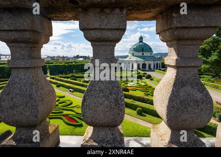 Blick durch das Geländer der barocken Kolonnade zum dekorativen Blumengarten, sonnigen Sommertag, kulatá historická budova im Zentrum, UNESCO Stockfoto