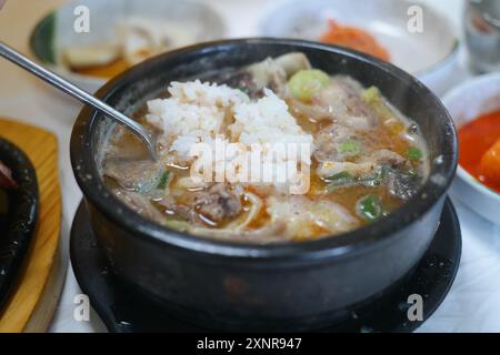 Reissuppe mit Schweinefleisch und Gemüse im heißen Topf auf Holztisch Stockfoto