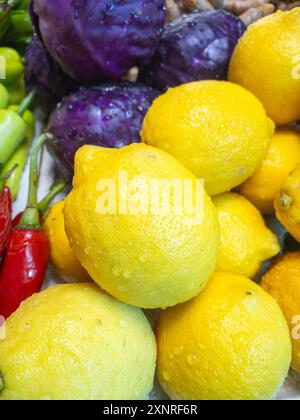 Nahaufnahme frischer Zitronen und Purpurkohl auf einem Markt, die ihre lebhaften Farben und Frische hervorheben. Stockfoto