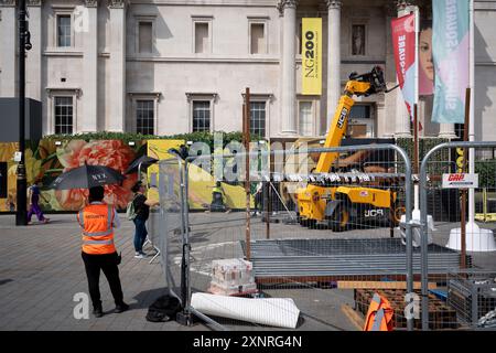 Ein Sicherheitsmann benutzt zur heißesten Zeit des Tages einen Regenschirm vor der National Gallery, die ihr 200-jähriges Bestehen feiert, am Trafalgar Square, wo am 31. August 2024 in London, England, ein Pavillon für die Aktivitäten der Sommerferienkinder gebaut wird. Stockfoto