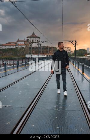 Mann, der auf der Brücke Dom Luis I läuft, mit dem Kloster Serra do Pilar im Hintergrund Stockfoto