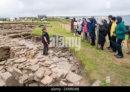 Ein Archäologe, der Besuchern eine Führung bei den Ausgrabungen von Ness of Brodgar auf dem Orkney-Festland gibt. Stockfoto