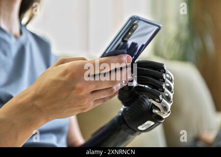 Junge Frau mit Prothese mit Handy auf der Couch Stockfoto