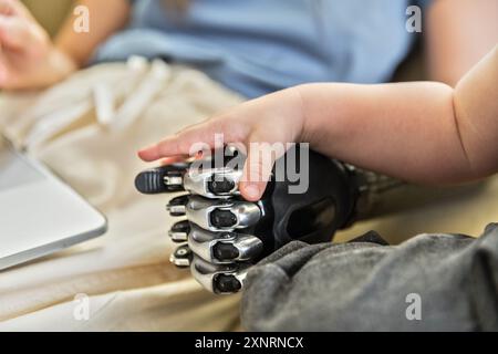 Kleiner Babyarm, der die Mutterprothese berührt Stockfoto