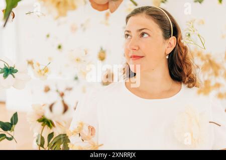 Frau umgeben von weißen und zarten Blumen, die ruhig aussehen Stockfoto