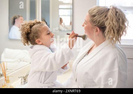 Die Tochter putzt im Badezimmer Make-up auf das Gesicht der Mutter Stockfoto