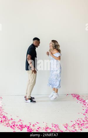 Mann und Frau interagieren freudig zwischen verstreuten rosa Blütenblättern Stockfoto