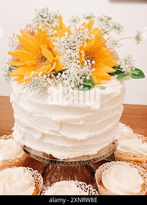 Weißer Kuchen, dekoriert mit Sonnenblumen und Babyatmung, umgeben Stockfoto