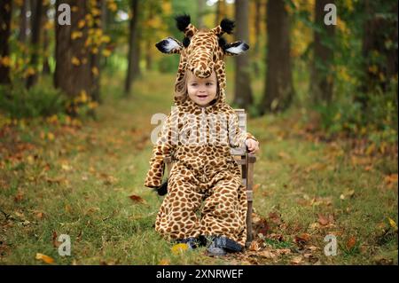 Glückliches kleines Mädchen, das ein Giraffen-Kostüm in bunten Wäldern trägt Stockfoto