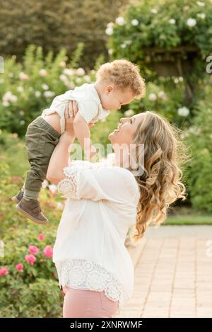 Mutter hebt den Sohn im Garten in die Luft Stockfoto