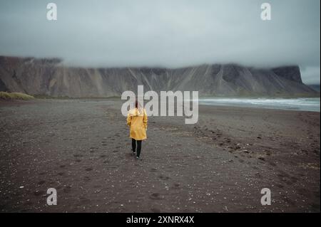 Frau, die an einem verregneten schwarzen Strand in Stokksnes, Island, läuft. Stockfoto