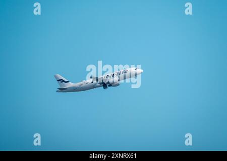 Helsinki/Finnland - 26. JULI 2024: Ein Airbus A319, der von der finnischen Fluggesellschaft Finnair betrieben wird, fliegt gegen einen hellblauen Himmel. Stockfoto