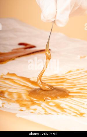 Goldenes Cannabiswachs mit einem Stock vom Papier abtupfen. Stockfoto