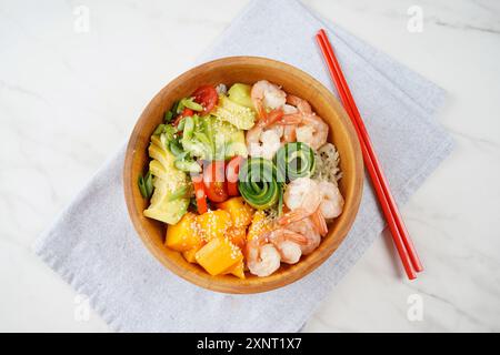 Frisches Meeresfrüchte-Rezept. Shrimps Poke Bowl mit Reis, grünen Zwiebeln, Tomaten, Avocado, Mango. Food Concept Poke Schüssel auf grauem Hintergrund Stockfoto