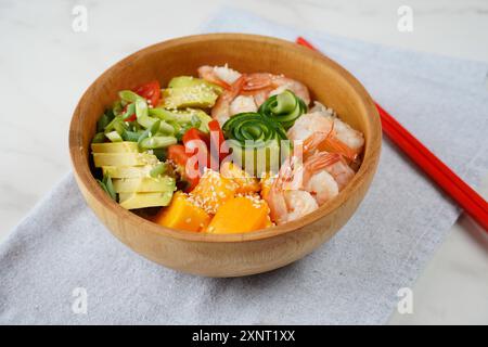 Frisches Meeresfrüchte-Rezept. Shrimps Poke Bowl mit Reis, grünen Zwiebeln, Tomaten, Avocado, Mango. Food Concept Poke Schüssel auf grauem Hintergrund Stockfoto