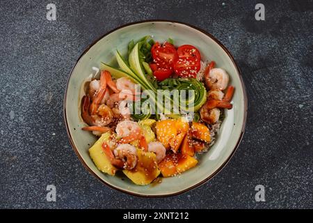 Frisches Meeresfrüchte-Rezept. Shrimps Poke Bowl mit Reis, grünen Zwiebeln, Tomaten, Avocado, Mango. Food Concept Poke Schüssel auf grauem Hintergrund Stockfoto