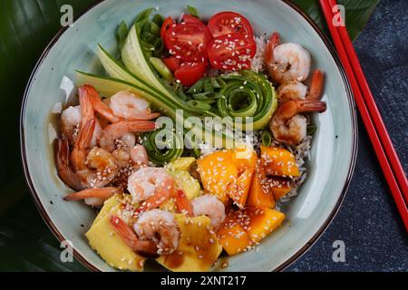 Frisches Meeresfrüchte-Rezept. Shrimps Poke Bowl mit Reis, grünen Zwiebeln, Tomaten, Avocado, Mango. Food Concept Poke Schüssel auf grauem Hintergrund Stockfoto