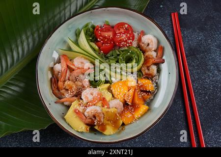 Frisches Meeresfrüchte-Rezept. Shrimps Poke Bowl mit Reis, grünen Zwiebeln, Tomaten, Avocado, Mango. Food Concept Poke Schüssel auf grauem Hintergrund Stockfoto