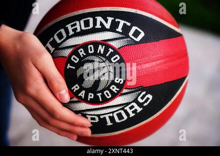 Ein Basketballspieler steht bereit, ein Toronto Raptors Ball in der Hand, während er den Sport übt. Stockfoto