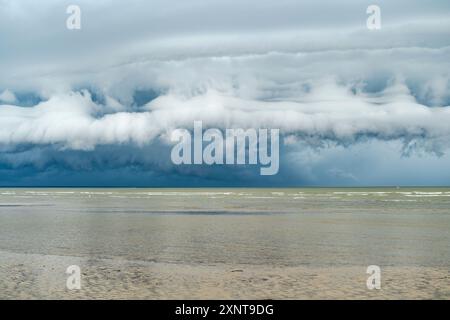 Sturmwolken bilden sich über einem Strand. Dichte, aufragende Regenwolke vor dem Sturm. Stockfoto