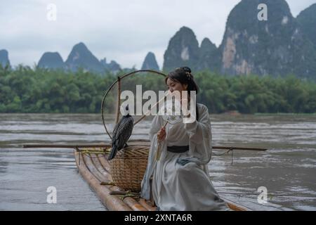 Junge chinesische Hanfu-Frau, die auf das Bambusfloß am Li River in Xingping hinunterschaut. Nahaufnahme Stockfoto