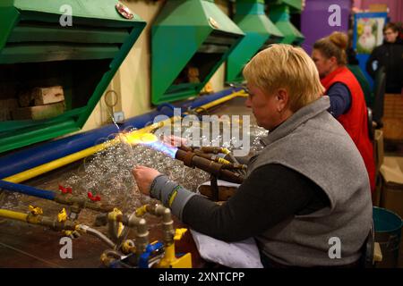 Weibliche Glasbläser blasen Glas blank machen Weihnachtsdekorationen sitzen in einer Produktionshalle. Dezember 10, 2018. Klavdievo, Ukraine Stockfoto