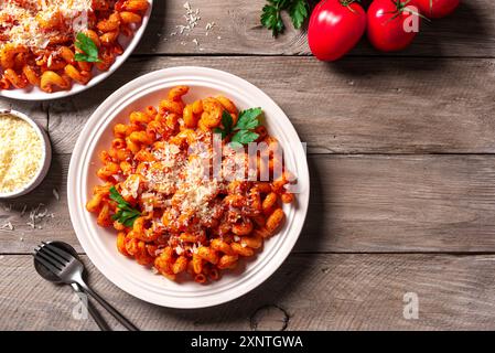 Cavatappi-Pasta mit Tomatensauce und geriebenem Parmesankäse auf hölzernem Hintergrund, Blick von oben. Hausgemachte vegetarische Nudeln mit reichhaltiger roter Sauce. Stockfoto