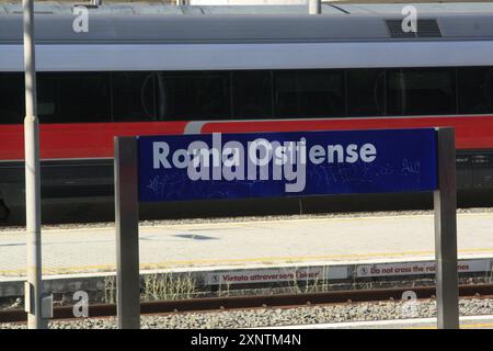 Ein Schild des Bahnhofs Roma Ostiense mit einem Zug im Hintergrund Stockfoto