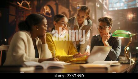 Verschiedene Gruppe von Studenten, die an einem Projekt in einer warm beleuchteten Bibliothek zusammenarbeiten. Junge Erwachsene, die sich an Diskussionen beteiligen, Laptop für E-Learning verwenden, umgeben von Bücherregalen mit akademischen Büchern Stockfoto
