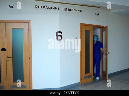 Krankenschwester in Gesichtsmaske und Laborkittel öffnet die Tür zur Abteilung eines Krankenhauses. Februar 2020. Kiew, Ukraine Stockfoto