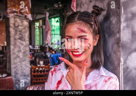 Porträt einer glücklichen kambodschanischen Kellnerin mit ihrem Gesicht für Halloween in einem Open-Air-Restaurant/Bar. Phnom Penh, Kambodscha. © Kraig Lieb Stockfoto