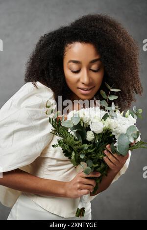 Eine wunderschöne afroamerikanische Braut in einem weißen Hochzeitskleid hält einen Blumenstrauß aus weißen Blumen. Stockfoto