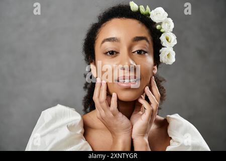 Eine wunderschöne afroamerikanische Braut posiert für ein Porträt, verziert mit weißen Blumen und einem strahlenden Lächeln. Stockfoto