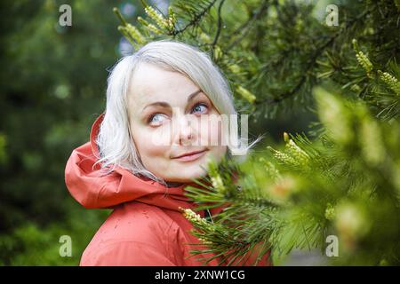 Schöne Frau in einer Korral Kapuzenjacke im Wald nach dem Regen Stockfoto