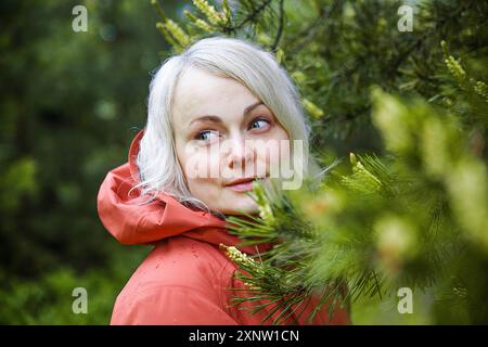 Schöne Frau in einer Korral Kapuzenjacke im Wald nach dem Regen Stockfoto