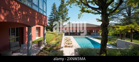 Großes Anwesen bestehend aus zwei roten Häusern, eines für Gäste und eines für die Eigentümer. Zwischen den beiden Gebäuden befindet sich ein wunderschöner Swimmingpool. Stockfoto