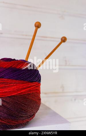 Bunte Stoffkugel mit Holzstricknadeln. Buntes Wollgarn mit Stricknadeln auf weißem Hintergrund. Handarbeit mit Kopierraum. Stockfoto