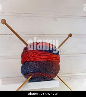 Bunte Stoffkugel mit Holzstricknadeln. Buntes Wollgarn mit Stricknadeln auf weißem Hintergrund. Handarbeit mit Kopierraum. Stockfoto