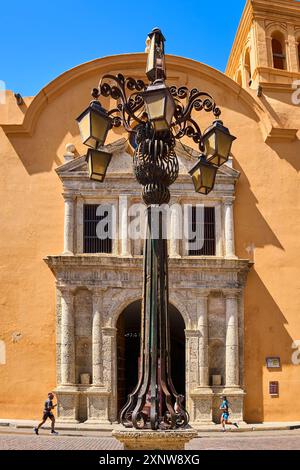 Eine klassische Straßenlaterne steht vor einem historischen Gebäude in Cartagena, Kolumbien, mit Fußgängern. Stockfoto