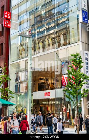 Das Flaggschiff Ginza Uniqlo Modegeschäft. Ladenvorderseite mit Schaufensterauslagen und Eingang mit Gehsteig voll mit Leuten, die draußen laufen. Stockfoto