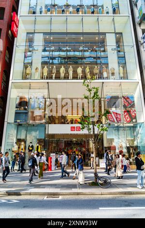 Das Flaggschiff Ginza Uniqlo Modegeschäft. Ladenvorderseite mit Schaufensterauslagen und Eingang mit Gehsteig voll mit Leuten, die draußen laufen. Stockfoto