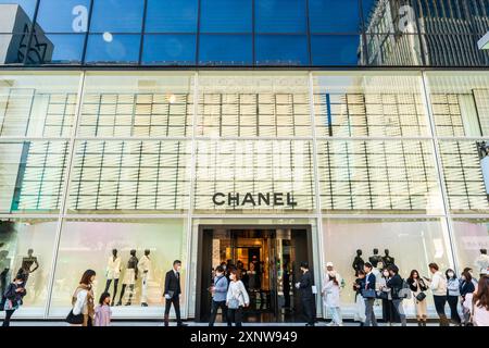 Leute stehen am Eingang des Chanel-Geschäfts in der Ginza in Tokio an. Männer in Anzügen auf beiden Seiten des Eingangs, um Kunden zu begrüßen. Stockfoto